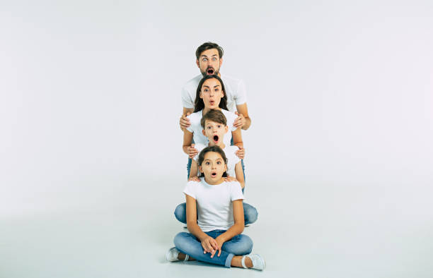 istock It's impossible! Very surprised family with opened mouths looking on camera isolated on white in T-shirts 1132216652