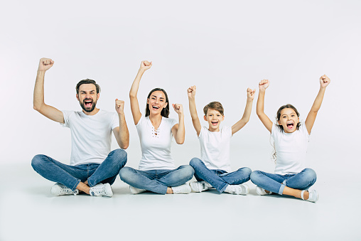 Happy and cheerful young beautiful family are smiling and posing while have a fun together over white background