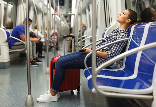 Portrait of tired young woman traveler in subway car