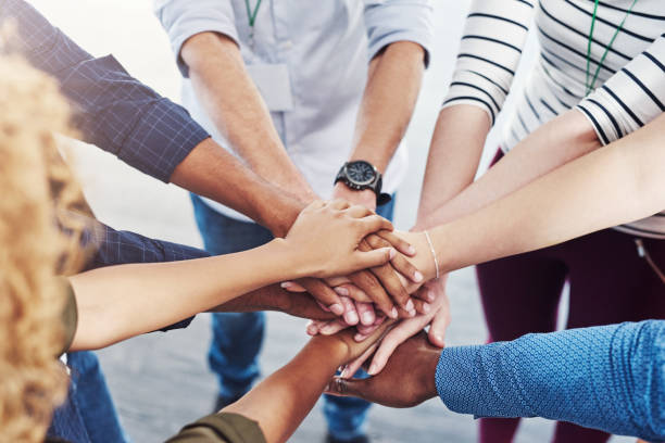 We're stronger when we unite together Closeup shot of a group of people joining their hands together in a huddle bonding stock pictures, royalty-free photos & images