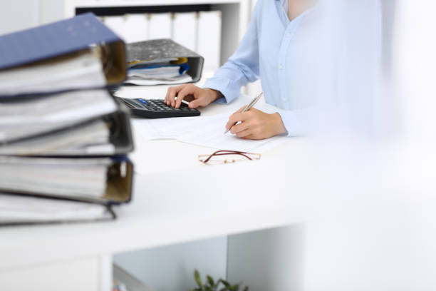 istock Unknown female bookkeeper or financial inspector calculating or checking balance, making report, close-up. Internal Revenue Service at work with financial document. Tax and audit concept 1132222738