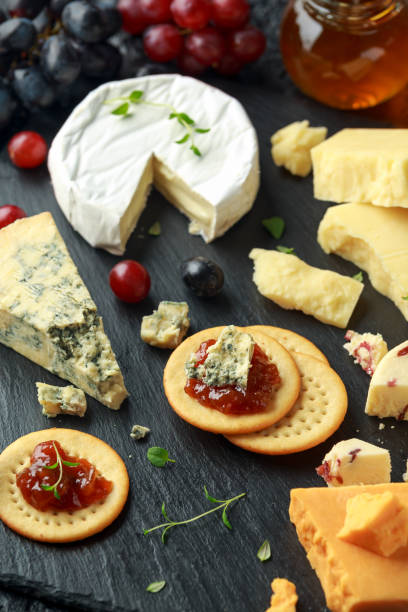 istock Cheese platter served with grapes, ale chutney, honey, crackers on stone board. Brie, cheddar, red leicester, wensleydale cranberries, blue stilton. 1132222909