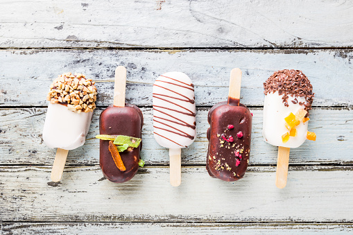 vanilla popsicles with chocolate coat and top with almond nuts and sweets on white background.