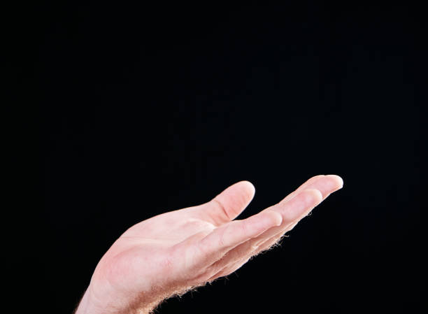 istock Raised hand on black background holding gap or begging 1132223877