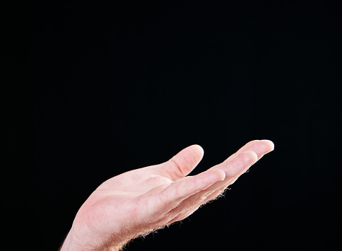 A hand is raised against a blank black background. The space above could be used for your copy or product or could indicate that the person is begging or appealing.
