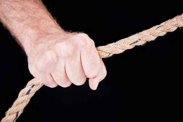 istock Hand grips thick rope against black 1132224506