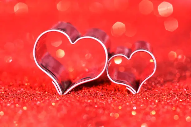 Hearts on red glitter with light reflections