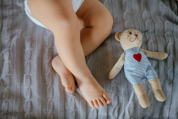 istock Cute baby legs and teddy bear 1132227403