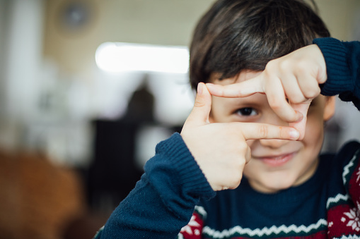 Boy makes a finger frame around his eye