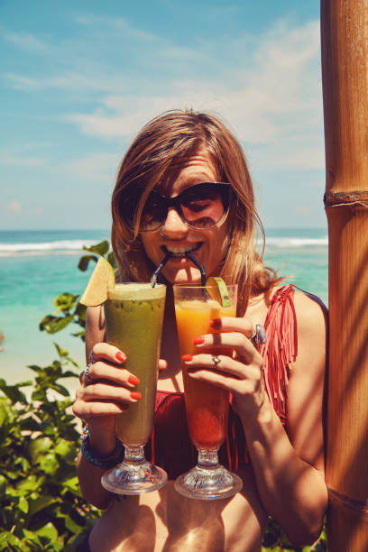 istock Beautiful woman drinking cocktail and using cellphone on the tropical sandy beach. 1132236381