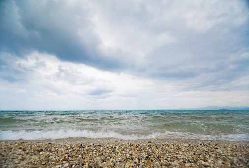 Seascape on an overcast day with high waves and clouds above the horizon.