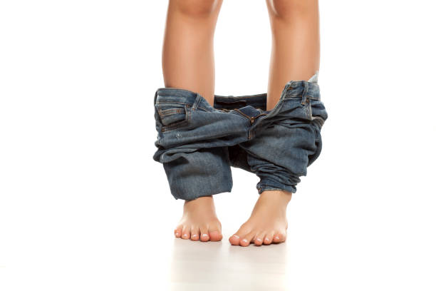 istock woman with her jeans down on white background 1132240104