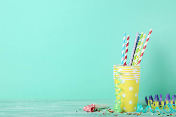 istock Yellow paper cups with straws and confetti on mint background 1132242116