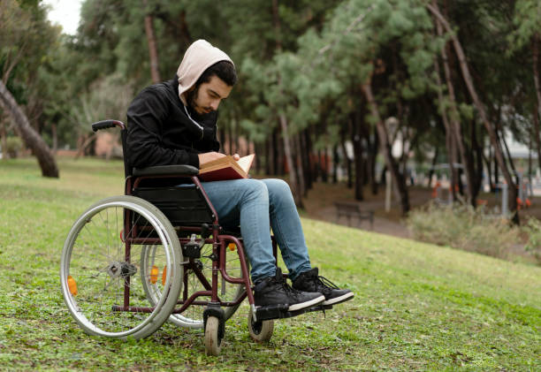 hombre joven discapacitado leyendo un libro - outdoors book reading accessibility fotografías e imágenes de stock
