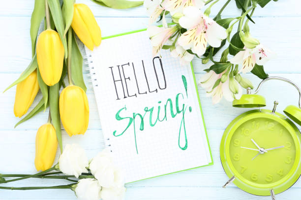 istock Fresh flowers with text Hello Spring and alarm clock on wooden table 1132244555