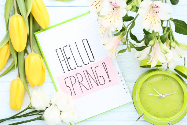 istock Fresh flowers with text Hello Spring and alarm clock on wooden table 1132246892