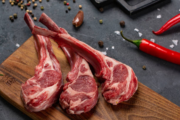 istock Raw meat on the bone with chilli and spices, black background for cooking with copy space, top view. 1132250940