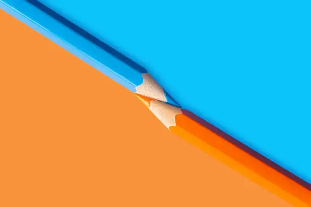 Photo of Two colored pencils separating the colored background diagonally