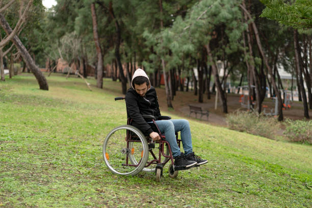 istock Young man sitting in wheelchair at park 1132257941