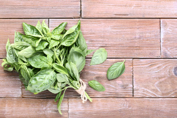 istock Green basil leafs on brown wooden table 1132258299