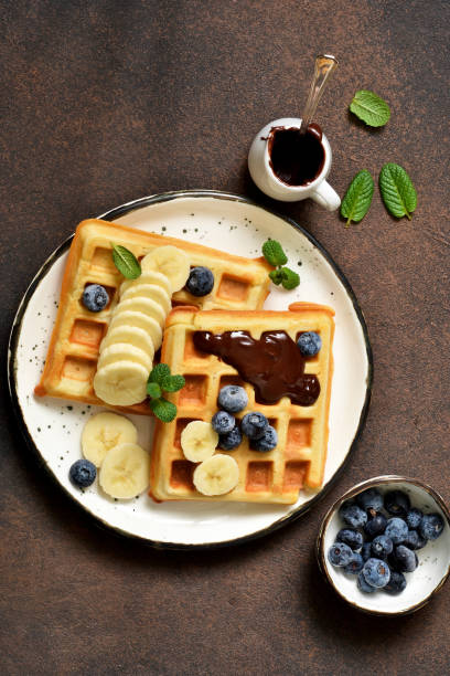 istock Breakfast time. Homemade waffles with banana, blueberry and chocolate spread on a kitchen table. 1132258609