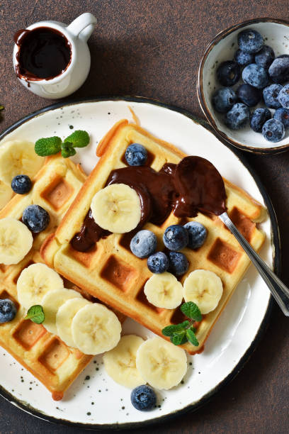 istock Breakfast time. Homemade waffles with banana, blueberry and chocolate spread on a kitchen table. 1132258772