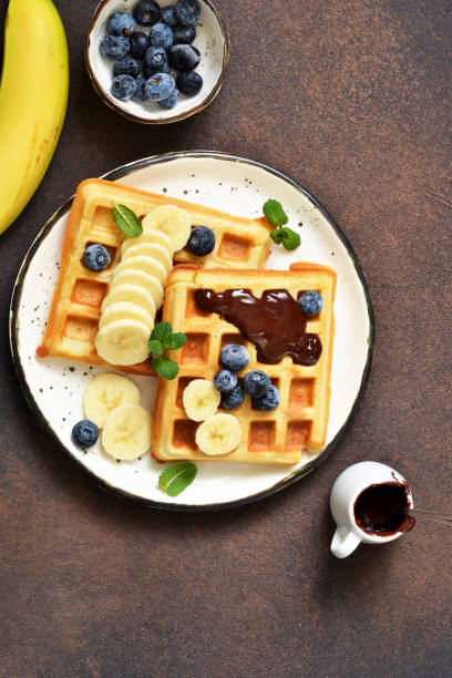 istock Breakfast time. Homemade waffles with banana, blueberry and chocolate spread on a kitchen table. 1132258774
