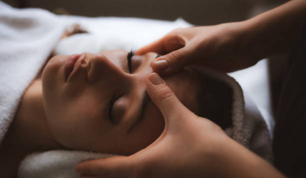 cropped hands of massage therapist massaging female customer in spa - massage table imagens e fotografias de stock