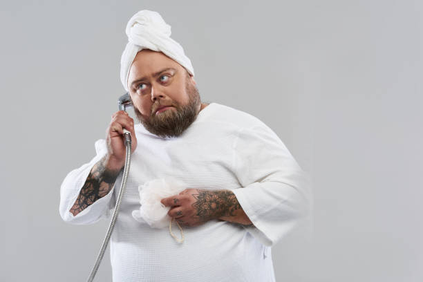 istock Funny overweight man having phone talk on the shower head 1132261553