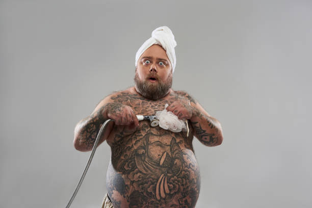 istock overweight shirtless man taking shower and looking surprised 1132261564