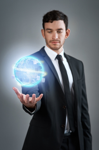 Studio shot of a young businessman holding a glowing orb against a gray background