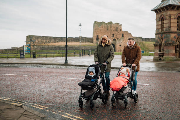 Crossing the Road Safely Two male friends are walking across a street, pushing their baby sons in strollers and chatting to one another. They are wearing warm clothing. baby stroller winter stock pictures, royalty-free photos & images