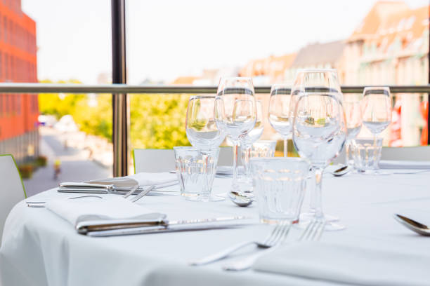 Empty glasses on a table covered with a white tablecloth in front of the panoramic window stock photo