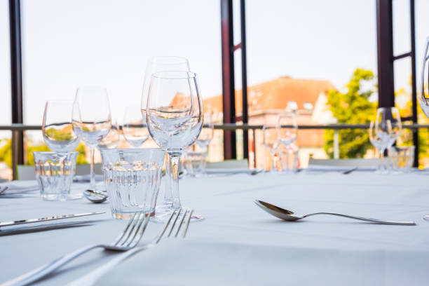 Empty glasses on a table covered with a white tablecloth in front of the panoramic window stock photo