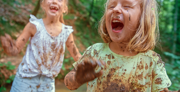 Smiling girls playing in wet mud.