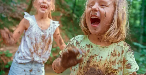 Smiling girls playing in wet mud.