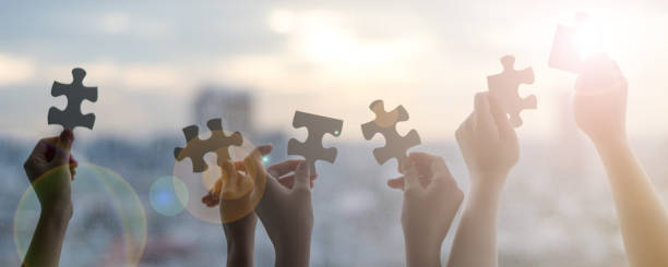 las manos de los niños estudiantes que sostienen los pieaces de jiwsaw juntos como un símbolo para el autismo o el trabajo en equipo en la escuela. - jigsaw puzzle teamwork puzzle red fotografías e imágenes de stock