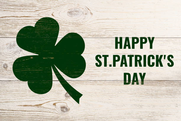 istock happy st. patrick's day, green text and clover leaf over white wooden wall 1132265945
