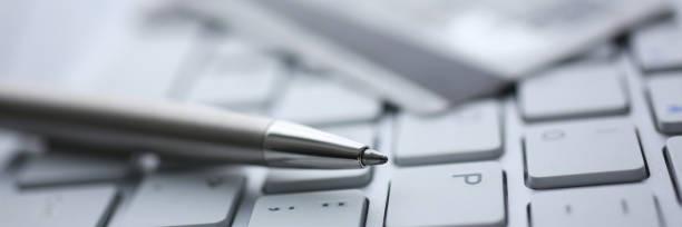 istock Silver pen with credit card lie white keyboard 1132266733