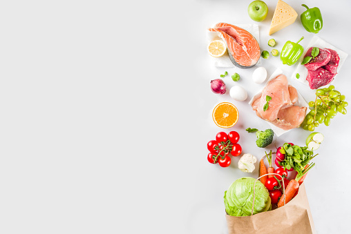 Healthy food shopping concept, Balanced diet ingredient - meat, fish, fruit, vegetables. Fresh foods with paper shopping bag, top view on white background copy space