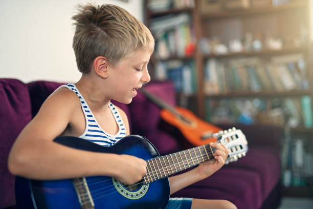 istock Little boy playing guitar and singing 1132271436