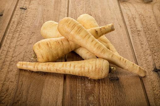Heap of parsnips roots on rustic wooden background