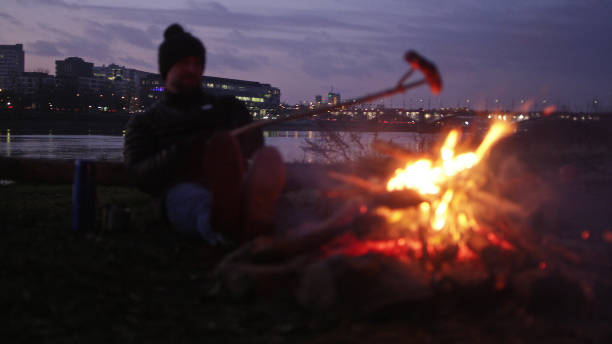 istock Lone man burning campfire on a riverside in big city 1132274731