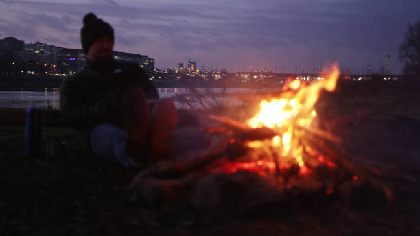 istock Lone man burning campfire on a riverside in big city 1132274749