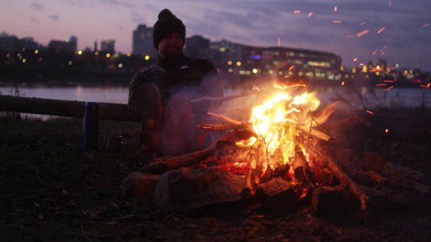istock Lone man burning campfire on a riverside in big city 1132275089