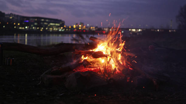 Camp fire burning on a riverside. City in background