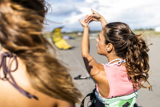 Female kiteboarding instructor explaining a woman basic techniques at the beach.