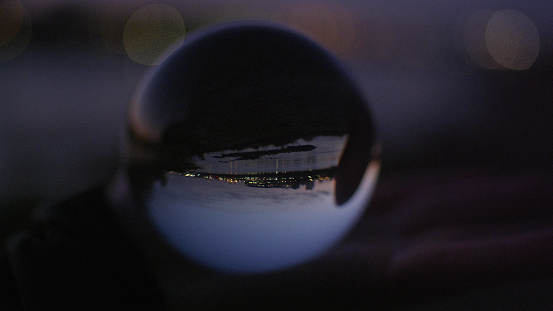 Glass ball with city view reflection. Moody sky during sunset