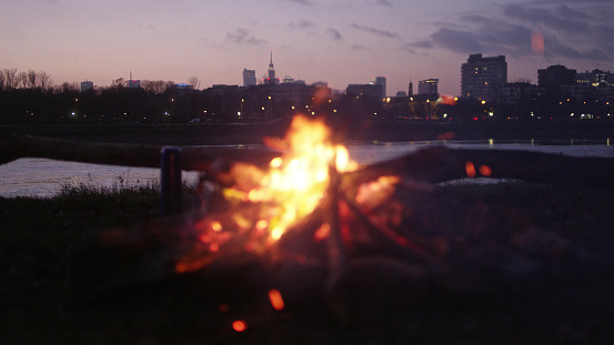 Fire burning on a winter evening. Sunset above river. City in background