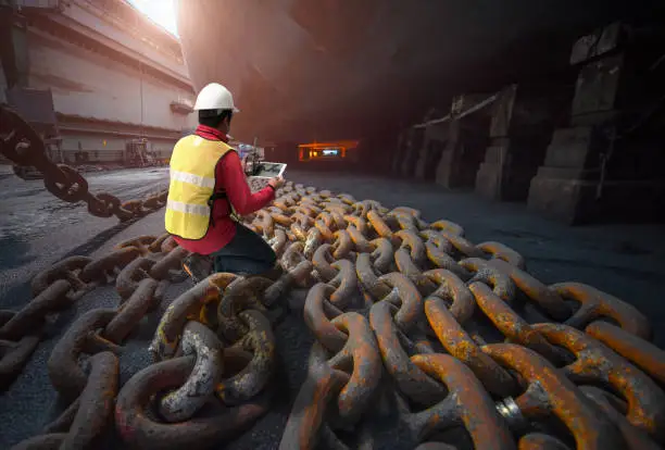 surveyor, inspector, port master inspect anchor chains bundle laying at bottom layer of the ship in floating dry dock terminal, for recondition maintennant with sand blasting perform